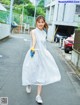 A woman in a white dress is walking down the street.