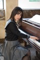 A young woman sitting at a piano in a room.